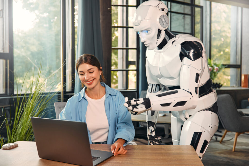 Robot And Woman Working On Laptop In Office